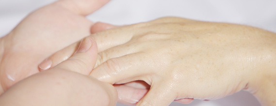 En hånd der får massage af to andre hænder